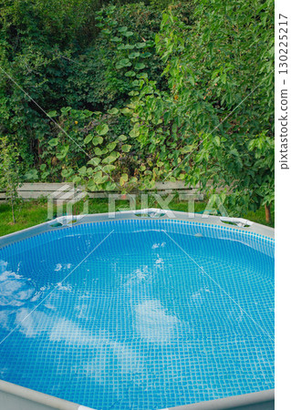 Frame swimming pool with clean water in the garden on a background of nature. Relaxation by the water. 130225217