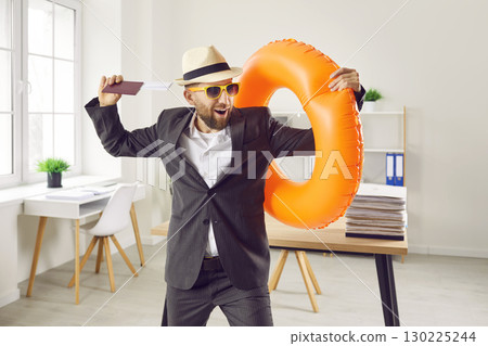 Happy business man standing in office holding tickets for summer vacation. 130225244