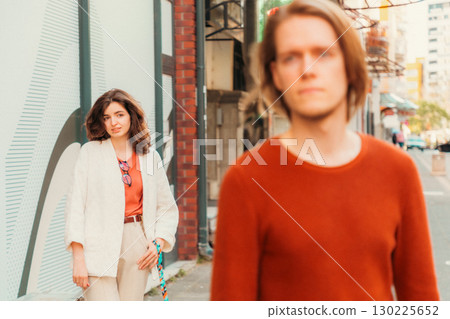 Young Caucasian woman smiling and looks at blurred handsome young man passing by on street. Psychology of relationship 130225652