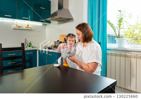 Family kitchen moment of mother and daughter learning and laughing together. Concept of early childhood education and love. Mid shot 130225660