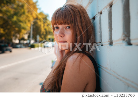 Summertime. Portrait of young pretty smiling woman with a tattoo posing by the white wall. The concept of freedom and psychology 130225700