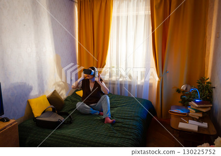 Caucasian woman tests immersive virtual reality equipment in bedroom. Leisure, technology use, and futuristic play at home. Wide shot 130225752