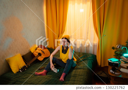 Girl sits comfortably in her bedroom and plays video games. Concept of independence and modern childhood. Wide shot, top view 130225762