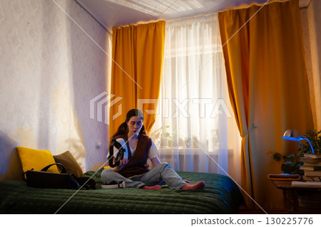 Tech savvy woman enjoys augmented simulation using VR headset in her bedroom. Innovative home entertainment concept. Low angle view, Wide shot 130225776