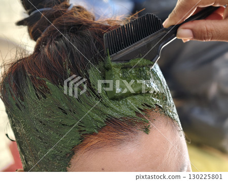 Close up of woman dyeing hair with natural green henna herbal paste 130225801