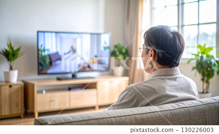Rear view of a senior man watching TV in the living room 130226003