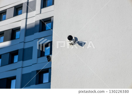 Security cameras are positioned on a light-colored wall of a contemporary building, emphasizing surveillance in an urban setting Security cameras are positioned on a light-colored wall of a contemporary building, emphasizing surveillance in an urban setting 130226380