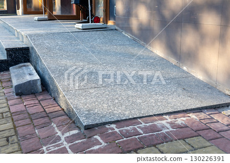 Accessible ramp provides smooth entry to a building with a contrasting brick walkway nearby during daylight hours Accessible ramp provides smooth entry to a building with a contrasting brick walkway nearby during daylight hours 130226391