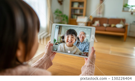 孫女和爺爺在客廳裡享受線上視訊通話 | 家裡的氣氛很溫馨 孫女和爺爺在客廳裡享受線上視訊通話 | 家裡的氣氛很溫馨 130226404