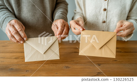 一對老夫婦在客廳遞上信封，木桌旁的溫馨家居場景 130226525