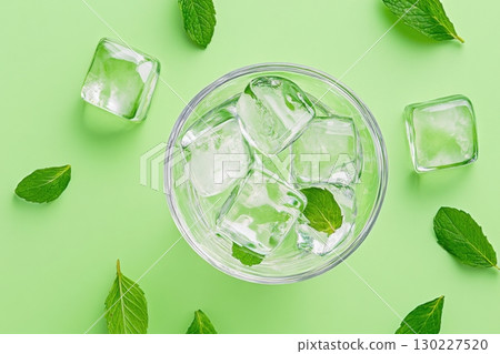 Refreshing drink with ice cubes and mint leaves on a vibrant green background perfect for hot days 130227520
