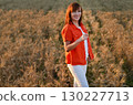 Woman meditating while sitting cross-legged in a golden wheat field during sunset hours for a sense of peace and tranquility 130227713
