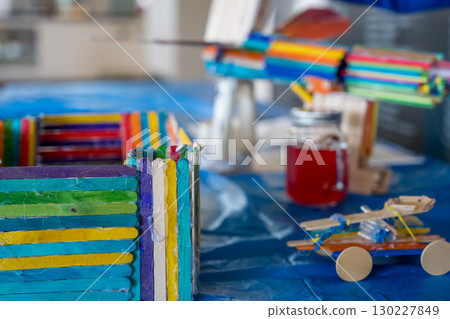 Crafting colorful toys and structures using popsicle sticks and other materials in a bright indoor space 130227849