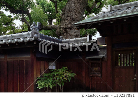 日本傳統建築的背景素材。平靜的大門和裝飾性的屋頂瓦片，以及一座惠比壽雕像。 130227881