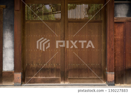 Background material of traditional Japanese architecture. The houses and trees can be seen through the wooden gate and latticework with a calm texture. Background material of traditional Japanese architecture. The houses and trees can be seen through the wooden gate and latticework with a calm texture. 130227883