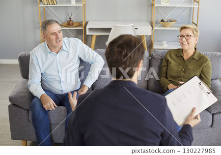 Senior couple talking to agent, discussing insurance agreement, real estate contract in agent office Senior couple talking to agent, discussing insurance agreement, real estate contract in agent office 130227985