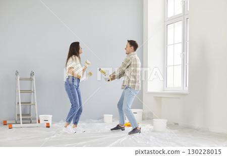 Married Couple Dancing and Having Fun Painting Walls in New Home 130228015