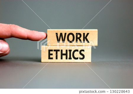 Work ethics symbol. Concept words Work ethics on beautiful wooden block. Beautiful grey table grey background. Businessman hand. Business and Work ethics concept. Copy space. 130228643