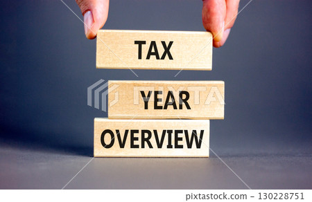 Tax year overview symbol. Concept words Tax year overview on beautiful wooden blocks. Beautiful grey background. Businessman hand. Business tax year overview concept. Copy space. Tax year overview symbol. Concept words Tax year overview on beautiful wooden blocks. Beautiful grey background. Businessman hand. Business tax year overview concept. Copy space. 130228751