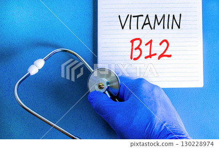 Vitamin B12 symbol. Concept words Vitamin B12 on beautiful white note. Doctor's hand in blue medical glove. Stethoscope. Beautiful blue background. Medical healthy lifestyle Vitamin B12 concept. 130228974
