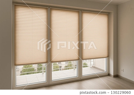 Three Beige Cellular Shades Covering Windows in a Bright Room 130229060