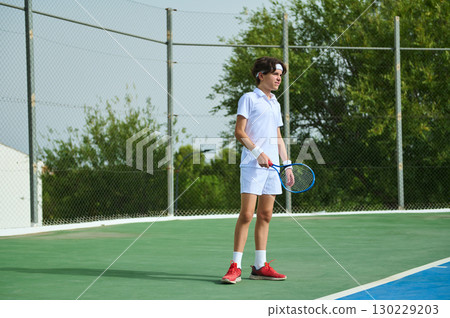 Teen Athlete Playing Tennis on Outdoor Court Under Sunny Sky 130229203