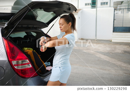 Woman Packing a Car Trunk with Fitness Gear on a Sunny Day 130229298