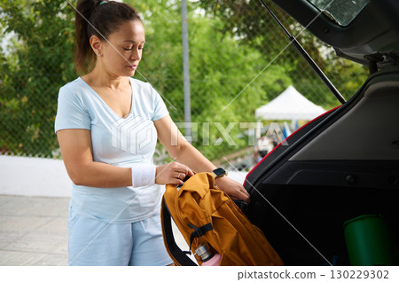 Woman Organizing Sports Gear in Car Trunk Before Outdoor Activity Woman Organizing Sports Gear in Car Trunk Before Outdoor Activity 130229302