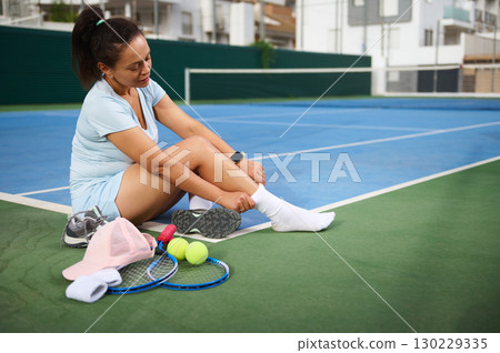 Woman Sitting on Tennis Court With Equipment After a Match 130229335