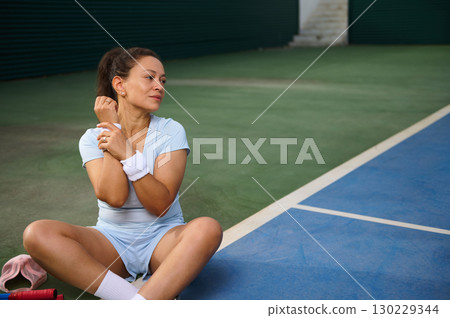 Woman Stretching After Exercise on an Outdoor Tennis Court Woman Stretching After Exercise on an Outdoor Tennis Court 130229344