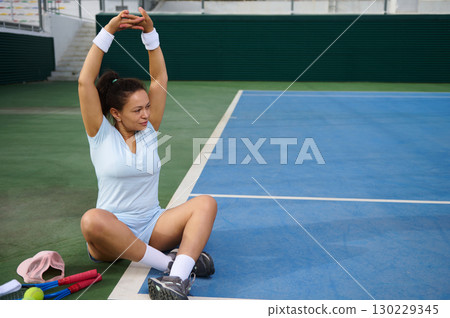 Young Woman Stretching on a Tennis Court After Practice 130229345