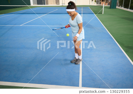 Woman Practicing Tennis Skills on Blue Court Outdoors During Daytime 130229355