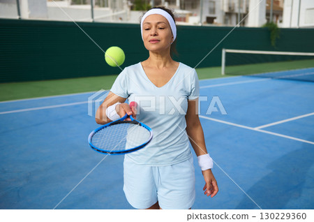 Woman Playing Tennis Practicing Ball Control on Outdoor Court 130229360