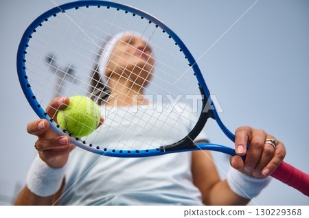 Woman Holding Tennis Racket and Ball Ready For Action on the Court 130229368