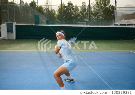 Focused Female Tennis Player Preparing to Return a Shot on Outdoor Court 130229381
