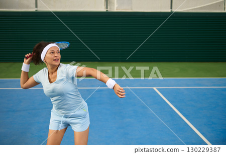 Female Athlete Playing Tennis on a Blue Court During Summer 130229387