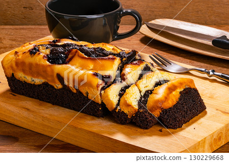 Blueberry cheese brownie with a metal fork and black ceramic coffee cup on wooden cutting board. Blueberry cheese brownie with a metal fork and black ceramic coffee cup on wooden cutting board. 130229668