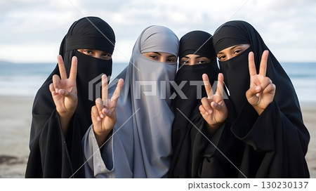 Four women wearing hijab making peace signs on a beach outdoors smiling Four women wearing hijab making peace signs on a beach outdoors smiling 130230137