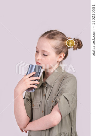 Young caucasian female child with lemon hair accessory holding smartphone Young caucasian female child with lemon hair accessory holding smartphone 130230581