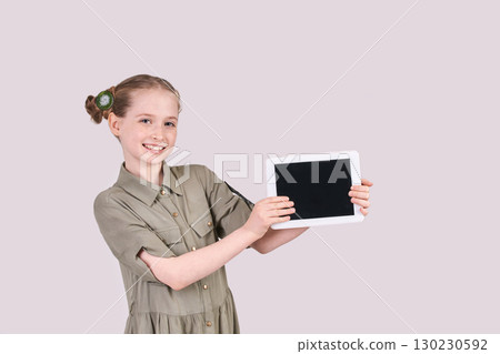 Caucasian young female child showing blank tablet screen with green dress 130230592