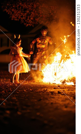 Child in costume dances with a character by flames 130231353