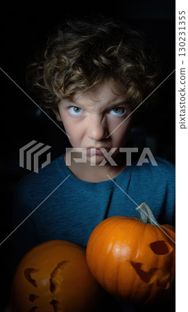 Boy with pumpkins displaying a serious expression 130231355
