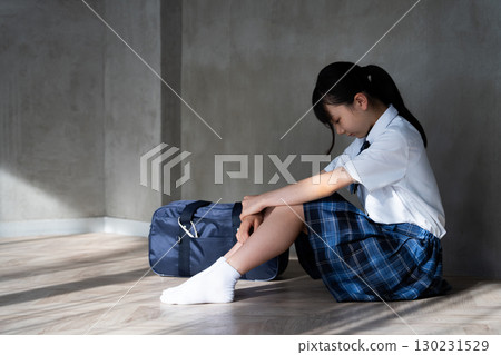 Side view of a female student sitting on the floor with her head down 130231529
