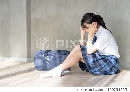 一名女學生抱著頭靠在書包旁邊 130231535