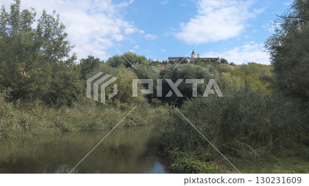Kosmodemyanskaya Church towering over lush vegetation and calm river 130231609