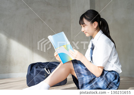 一位微笑的女學生閱讀課本的畫像 130231655