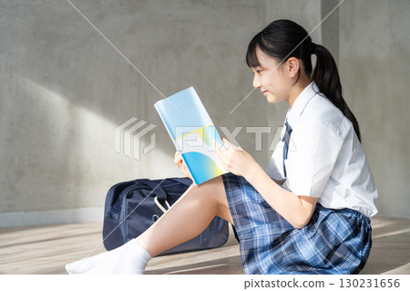 一位微笑的女學生閱讀課本的畫像 一位微笑的女學生閱讀課本的畫像 130231656
