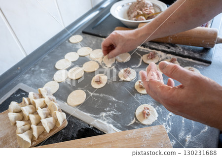 Man preparing dumplings dough on gray table in the kitchen. Food concept. Man preparing dumplings dough on gray table in the kitchen. Food concept. 130231688