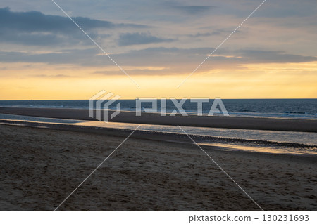 Sunset on the beach near beautiful sea in the evening. Boat and yellow sunlight. Vacation in Ostende, Belgien. Sunset on the beach near beautiful sea in the evening. Boat and yellow sunlight. Vacation in Ostende, Belgien. 130231693