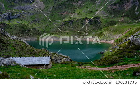 A serene, emerald-green mountain lake is nestled within a verdant valley in Somiedo Natural Park, Asturias, Spain. A serene, emerald-green mountain lake is nestled within a verdant valley in Somiedo Natural Park, Asturias, Spain. 130231739